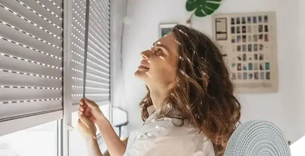 Femme manœuvrant la sangle d'un volet roulant